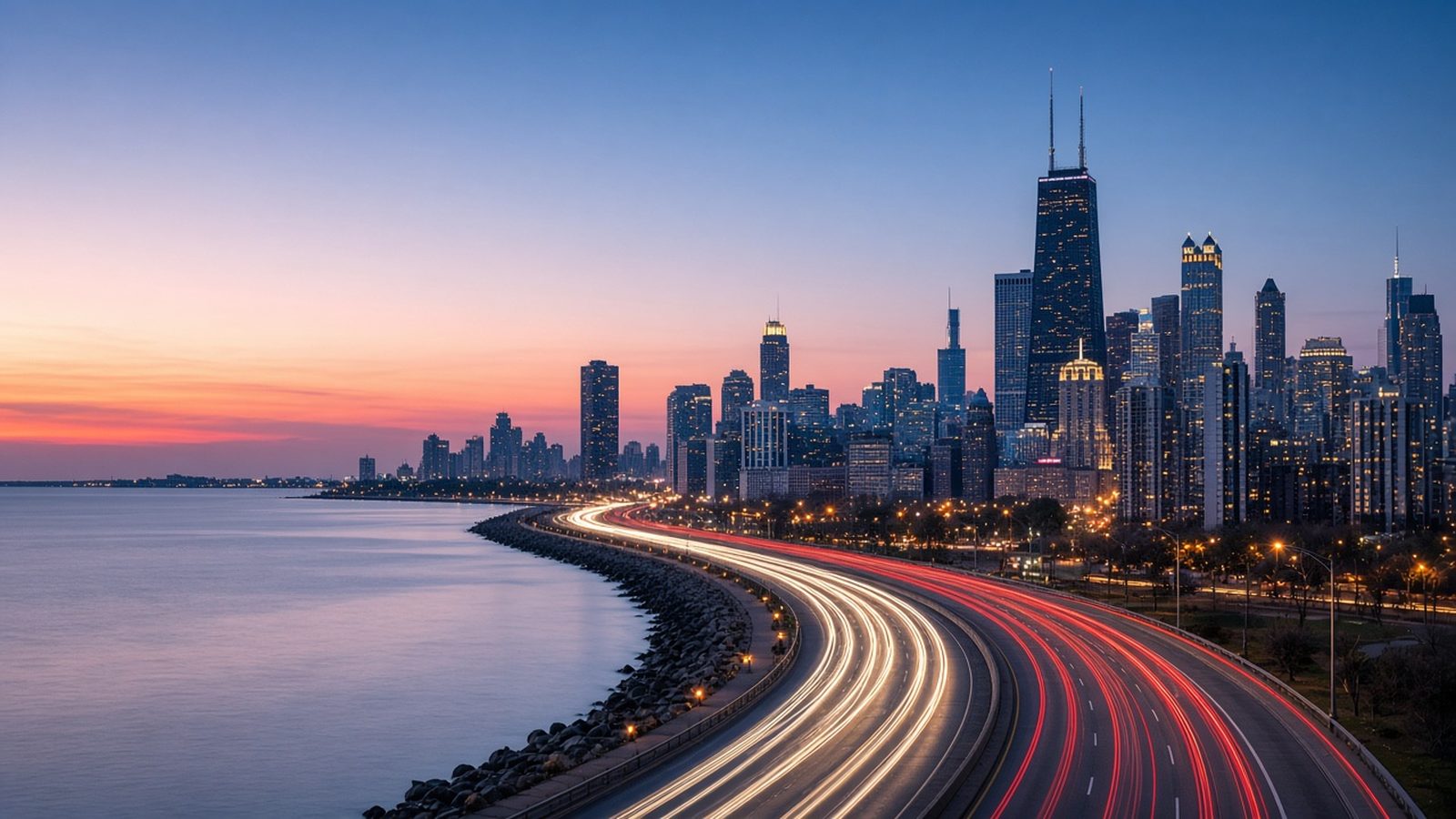 Long-exposure view of Lake Shore Drive at dusk with soft light trails and the Chicago skyline in the background